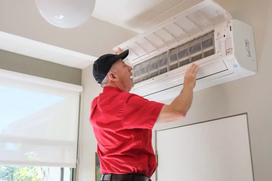 A John Owens Services technician servicing a wall-mounted mini-split